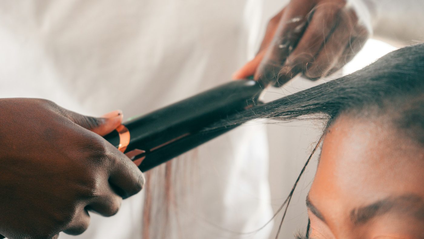 Dark hair being smoothed with a flat iron